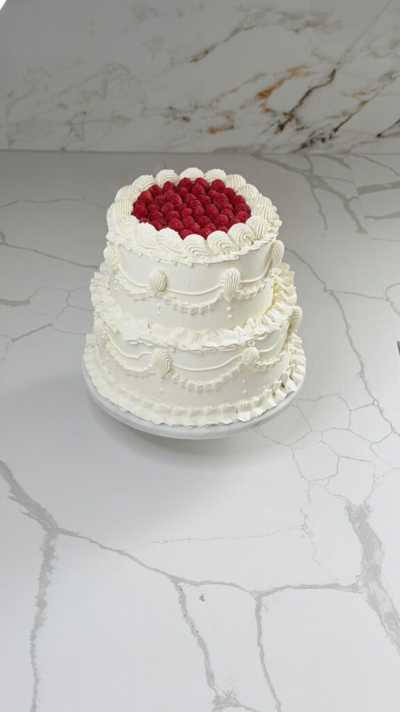 Two-tier vintage cake topped with fresh raspberries
